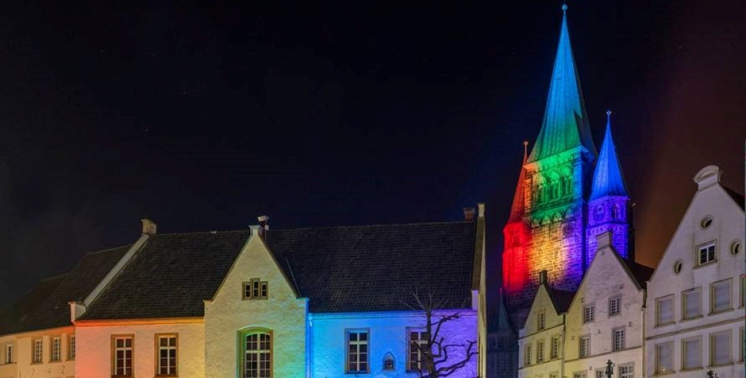 Spektakuläre Lichtinstallation: Nachdem in Warendorf mehrfach Regenbogenfahnen vor Kirchen abgerissen und gestohlen wurden, fand die Gemeinde der St.. Laurentius-Kirche eine andere Form des Protestes, sie beleuchtet ihren Kirchturm in Regenbogenfarben. Aus Solidarität schloss sich die Stadtgemeinde der Aktion an und taucht auch das benachbarte Rathaus in buntes Licht (Foto: André Auer, Stadt Warendorf / via Peter Lenfers, St. Laurentius)