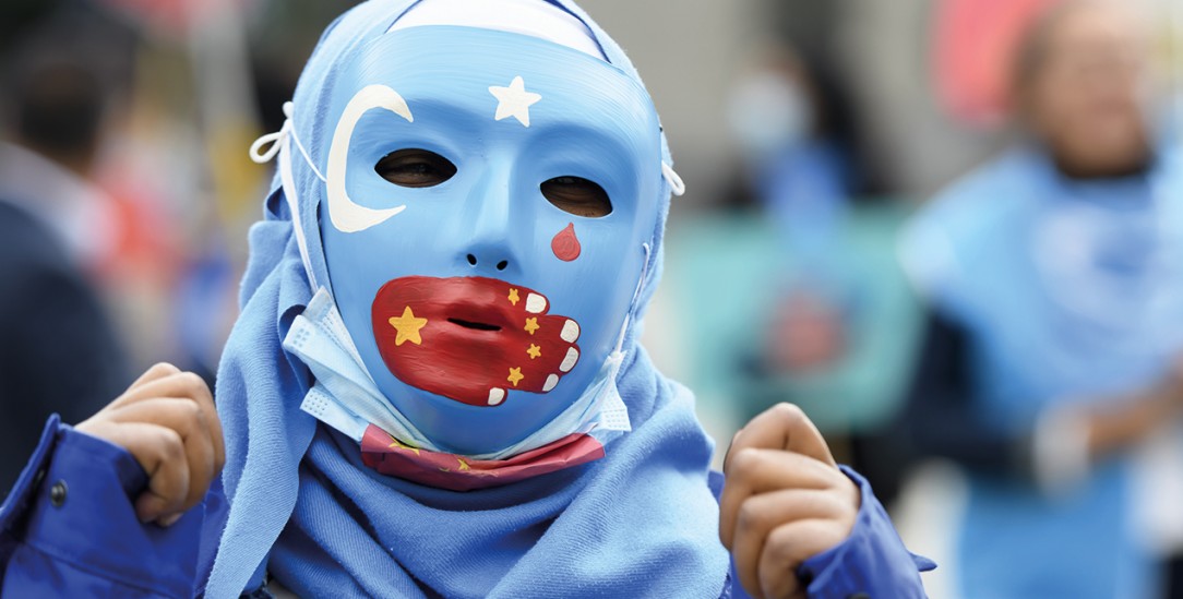 Protest mit Maske: Eine chinesische Hand auf dem Mund steht für die Unterdrückung der Uiguren